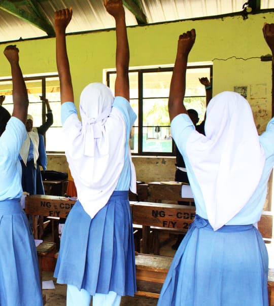 Grade 7 learners with their hands raised during an ice breaker at Jego